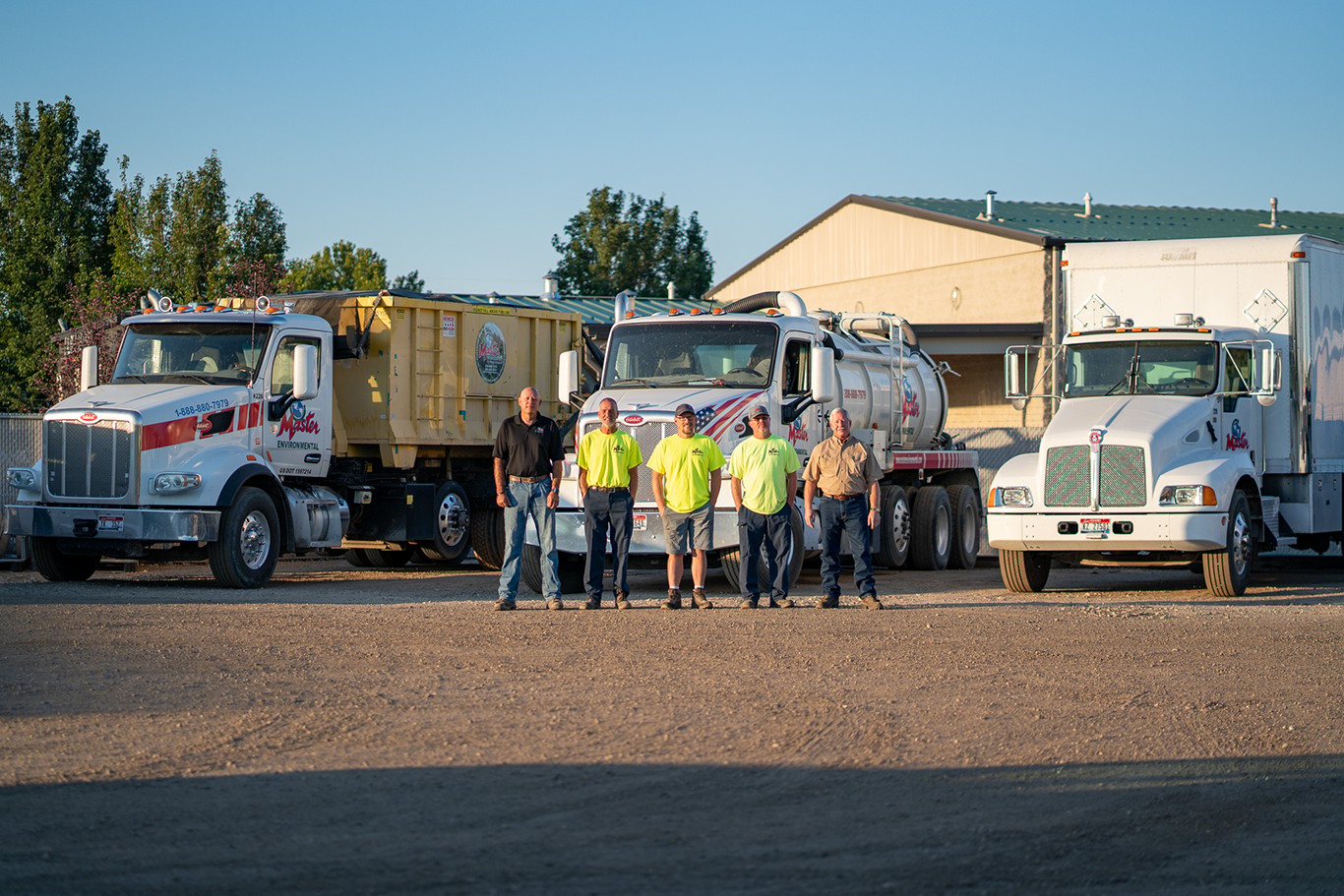 Master Environmental team standing with branded service trucks